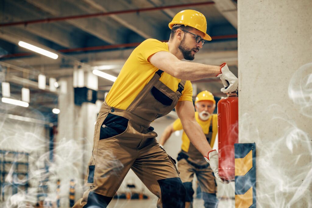 Young man using fire extinguisher in warehouse