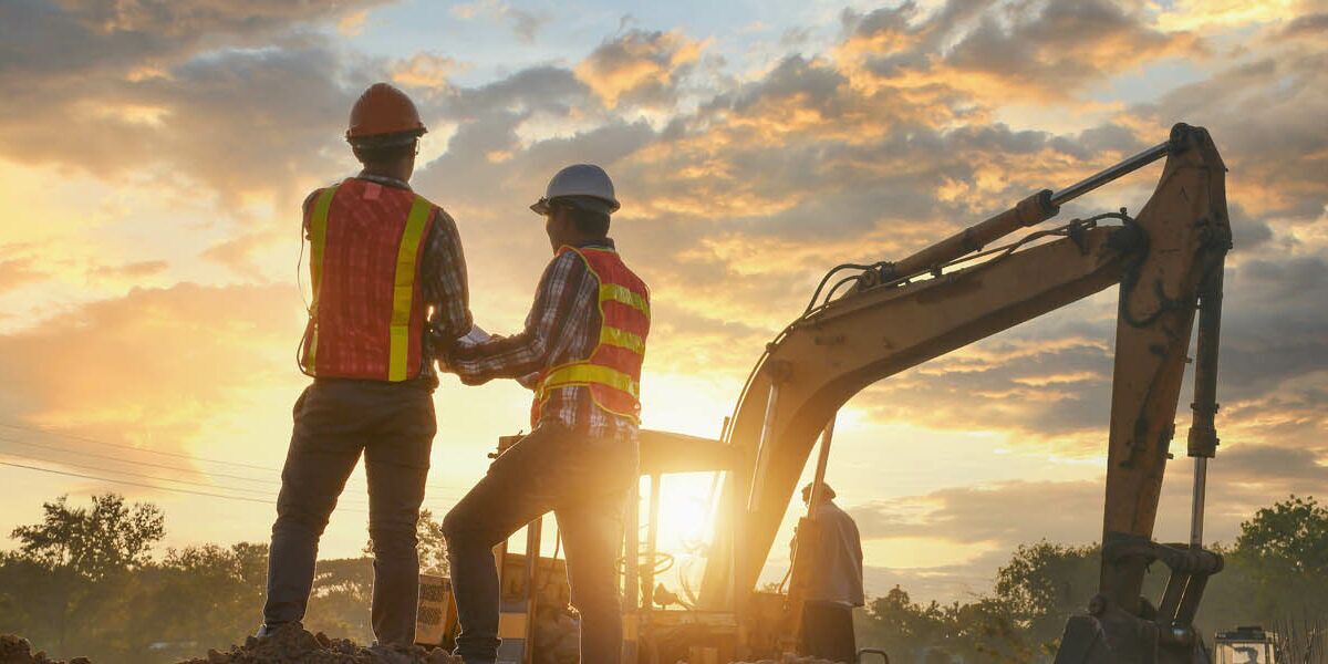 Construction engineers supervising progress of construction project stand on new factory,Engineering Consulting People on construction site holding blueprint in his hand. Building inspector.