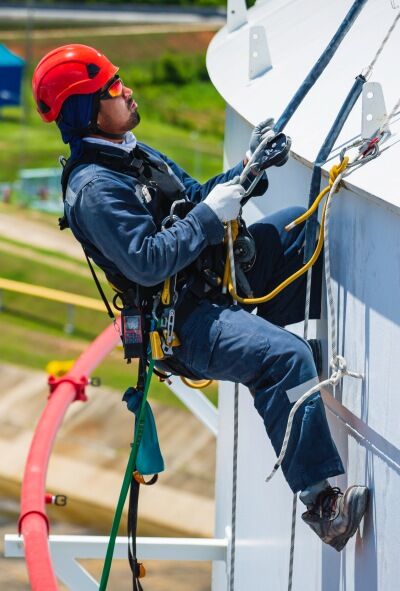 Male worker down height tank roof rope access safety inspection of thickness storage tank gas propane.
