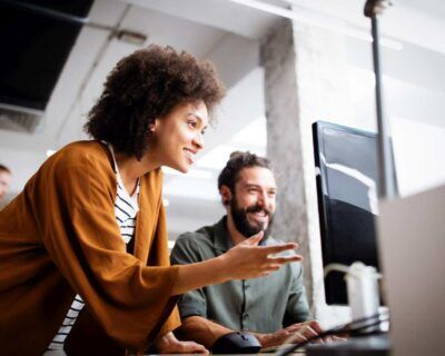 woman describes and teaches coworker how to use HR tool