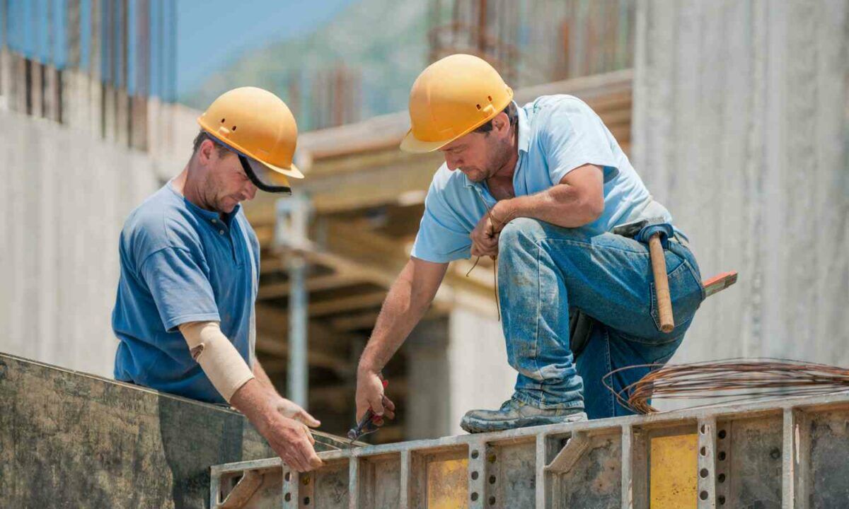 Two construction workers installing concrete formwork frames