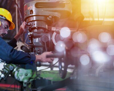 Professional industrial engineer, technician, factory worker wear hard hat, safety glasses. While checking, set up, control machine heavy industry factory. Employee working in manufacturing facility.