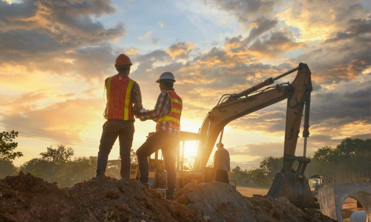 Construction engineers supervising progress of construction project stand on new factory,Engineering Consulting People on construction site holding blueprint in his hand. Building inspector.