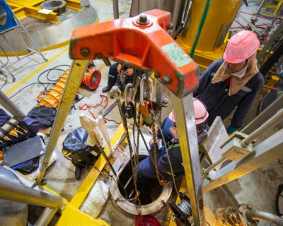 Confined space entry team using tripod and retrieval system for worker access.