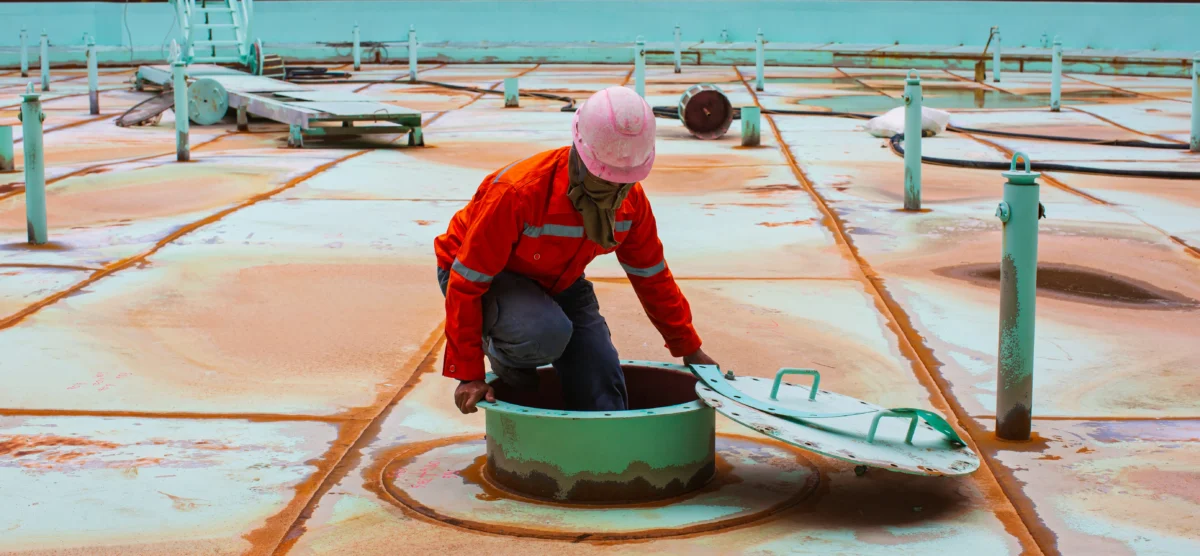 Worker in safety gear performs a confined space inspection as part of workplace safety procedures.