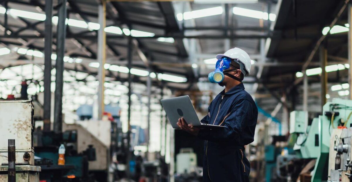 Officials from the Department of Hazardous substances control bureau is investigating the leak of a hazardous chemical in a chemical plant. Man with protective mask and computer laptops in factory