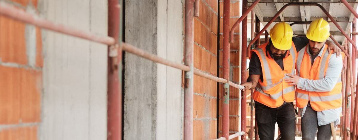 Manual Worker Helping Injured Colleague In Construction Site