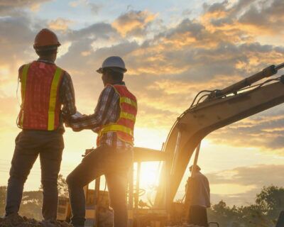 Construction engineers supervising progress of construction project stand on new factory,Engineering Consulting People on construction site holding blueprint in his hand. Building inspector.
