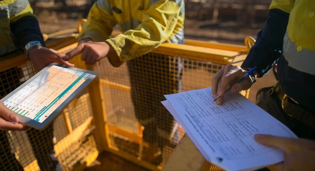 Crew using tablet and paperwork during jobsite onboarding for safety and compliance.