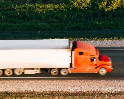 Truck driver near a semi-truck at sunset, symbolizing Hours of Service training. Commercial driver steering truck at sunrise, focusing on safe and compliant driving.