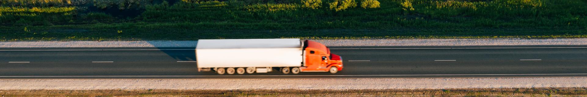 Truck driver near a semi-truck at sunset, symbolizing Hours of Service training. Commercial driver steering truck at sunrise, focusing on safe and compliant driving.