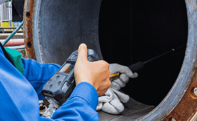 Worker female hand holding gas detector inspection safety gas testing at front manhole tank chemical