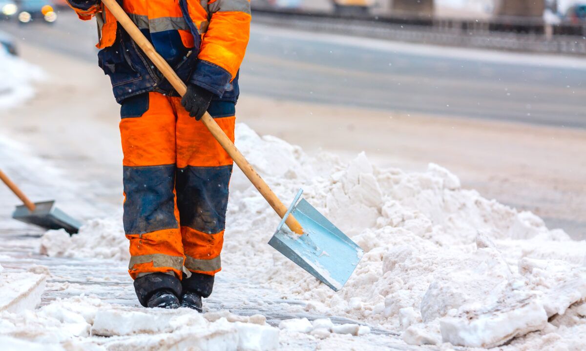 Facility crew shoveling snow on a sidewalk in freezing conditions as part of winter safety maintenance.