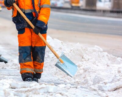 Facility crew shoveling snow on a sidewalk in freezing conditions as part of winter safety maintenance.