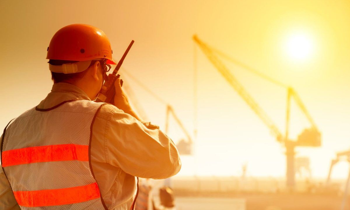 worker with large crane site and sunset background